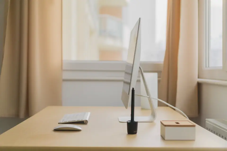 A tidy desk by a window with a desktop computer, keyboard and mouse