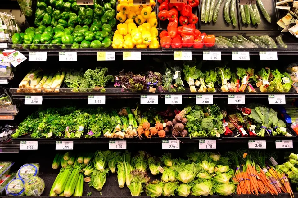 Supermarket shelves stocked with peppers, leafy greens, celery and carrots