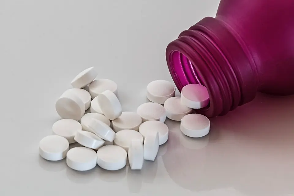 White tablets spilling from a tipped-over purple bottle