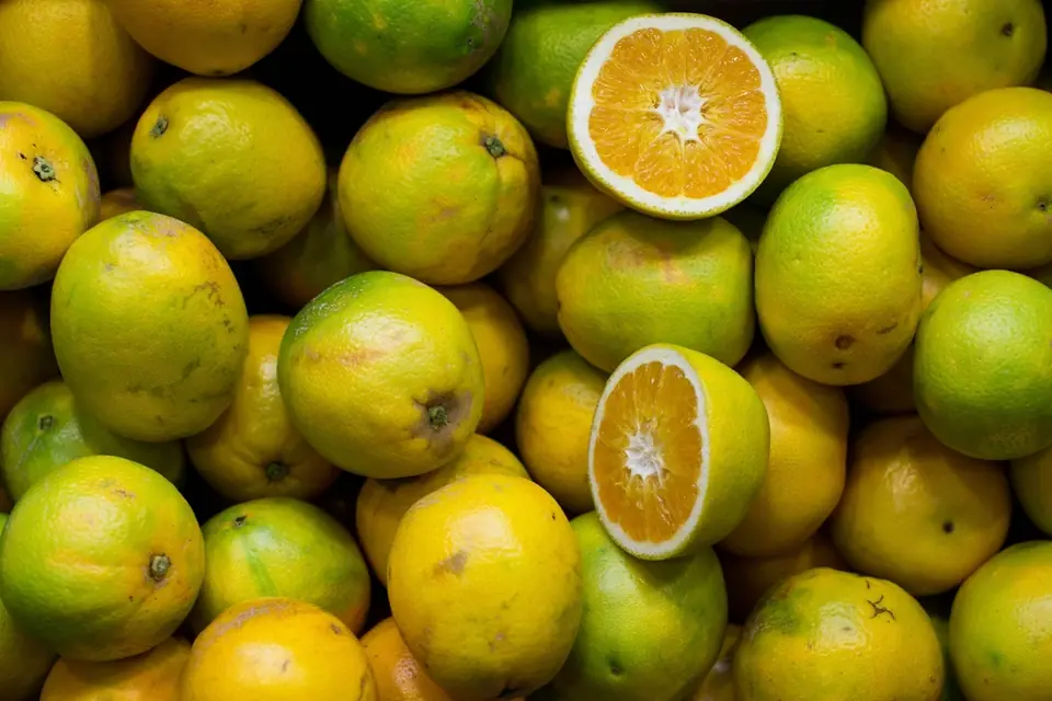 A pile of green and orange citrus fruits, two of them cut in half